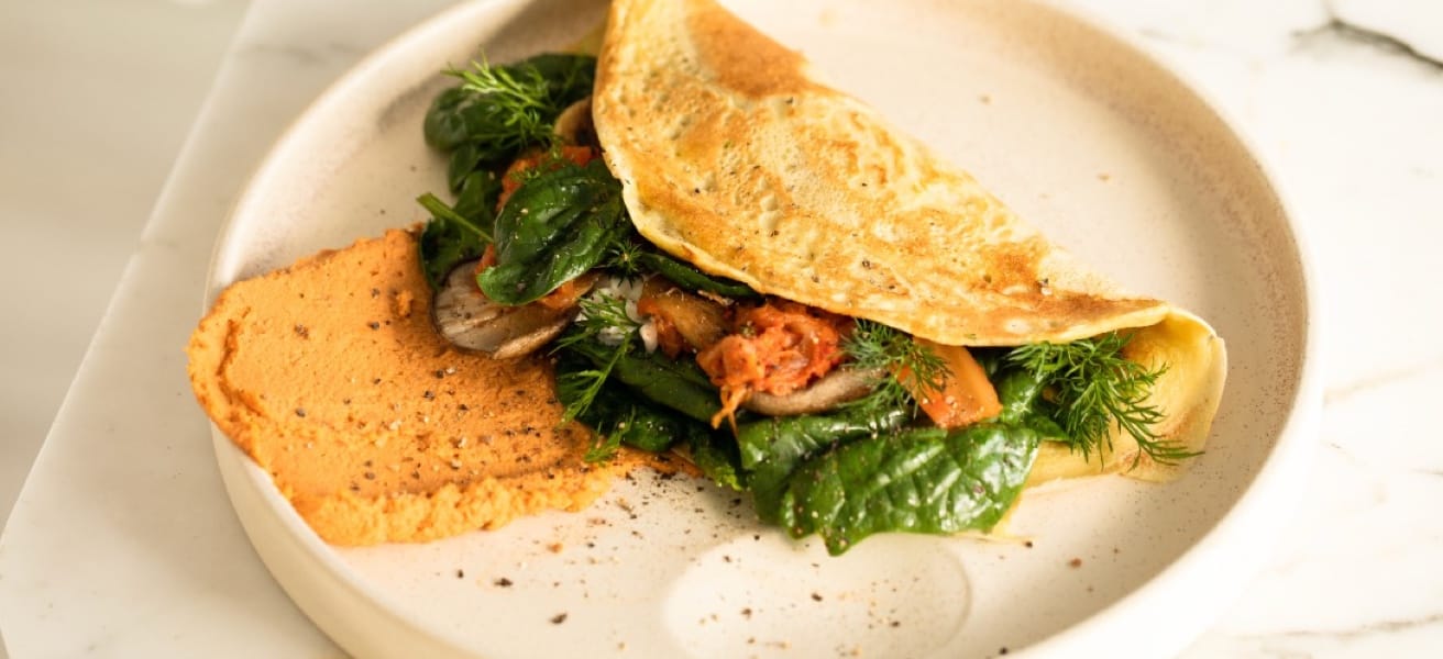 A golden-brown omelette garnished with herbs and served on a white plate